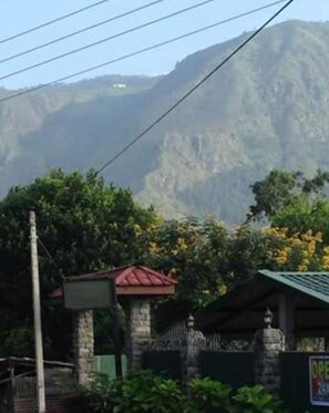 A stone building with a red roof, surrounded by lush greenery and a mountain in the background. - Hamadhi Guest (Hildummulla)