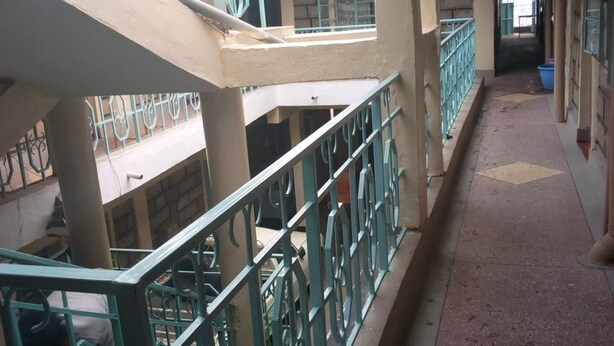 A multi-level corridor with green railings and a tiled floor.