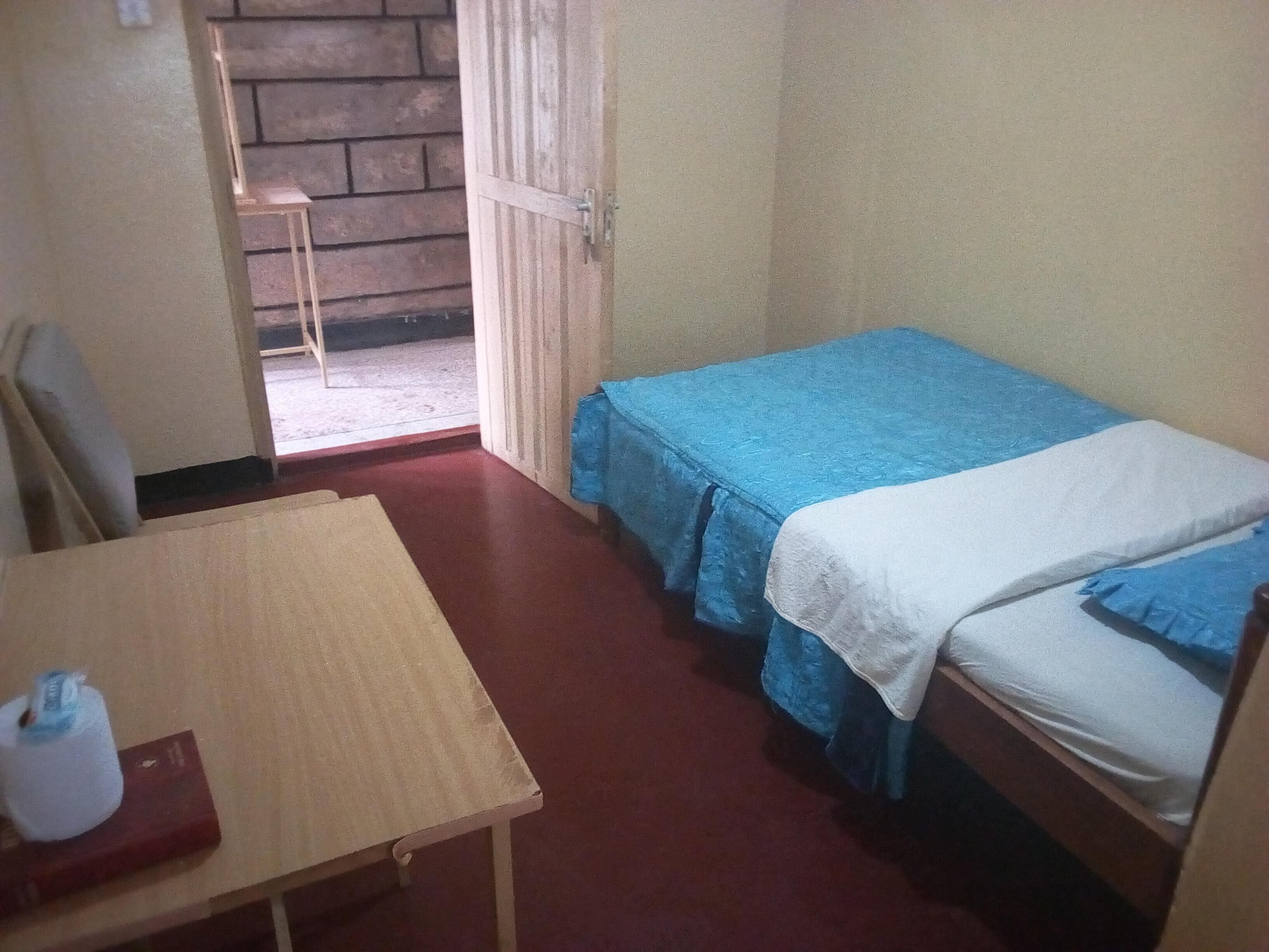 A small room with two beds, a table, and a chair.