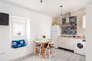 A compact kitchen with a dining area, a washing machine, and a window with a view.