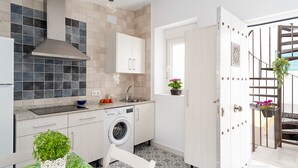 Een kleine keuken met een wasmachine, een spoelbak en een eethoek met een stoel en tafel.