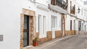 Een smalle straat met witte gebouwen, elk met een stenen fundering en een balkon.