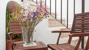 Een houten stoel en tafel met een glazen vaas gevuld met bloemen.