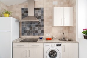 A compact kitchen with a built-in washing machine, a sink, and a stove.