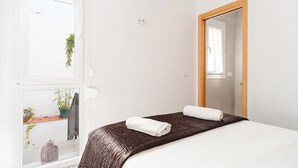 Een hotelkamer met een bed, een raam met uitzicht, een spiegel en een deur.