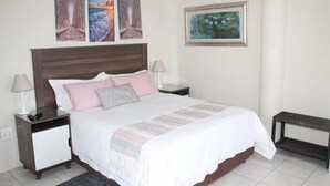 Een netjes ingerichte slaapkamer met een groot bed, twee nachtkastjes en een bankje.