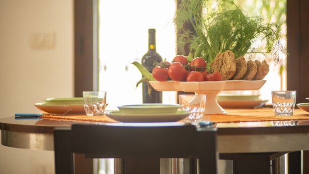 A dining table with plates, glasses, a bottle, and a bowl of food. - Historical charm in Racale (Racale)