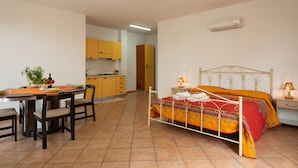 A bedroom with a bed, bedside table, and a dining area with chairs and a table. - Historical charm in Racale (Racale)
