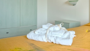 Quarto com cama, guarda-roupa, mesa de cabeceira e luminária na parede.