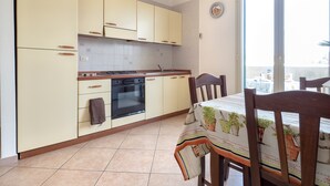 Uma cozinha com armários, fogão, forno e uma área de jantar com cadeiras e mesa.