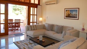 A living room with a sectional sofa, a coffee table, and a dining area with chairs and a table. - Villa 32 - Limni (Kouklia)