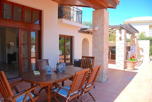 A patio with a wooden table and chairs, a stone pillar, and a sign indicating a pool area.