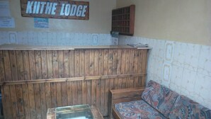 A room with a wooden bench, a patterned sofa, and a sign reading "Kiithe Lodge".