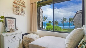 A bedroom with a large window offering a view of the ocean and palm trees. - Sealodge H5: Delightful Oceanview Condo, Close to Beaches & More (Princeville)