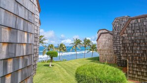A building with a view of the ocean and palm trees. - Sealodge H5: Delightful Oceanview Condo, Close to Beaches & More (Princeville)