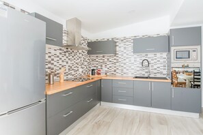 Une cuisine moderne avec des meubles gris, un pare-feu en carreaux et un four à micro-ondes encastré.