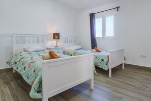 Une chambre avec deux lits, une table de chevet, une lampe et une fenêtre avec des rideaux.