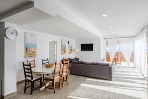 A modern living room with a dining area, a sofa, and a flat-screen TV.
