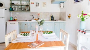 A kitchen with a wooden table set for a meal, a small refrigerator, and a sink.