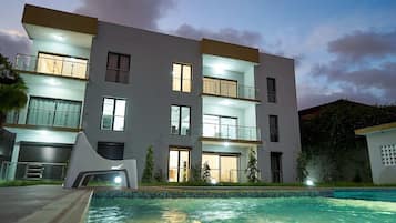 Un immeuble à plusieurs étages doté de balcons, d’une piscine et d’un éclairage extérieur soigné.