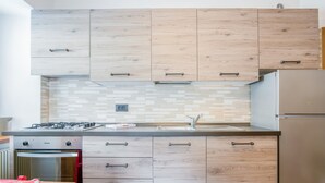 Eine moderne Küche mit Holzausstattung, einem Gasherd, einem Backofen und einem Kühlschrank.