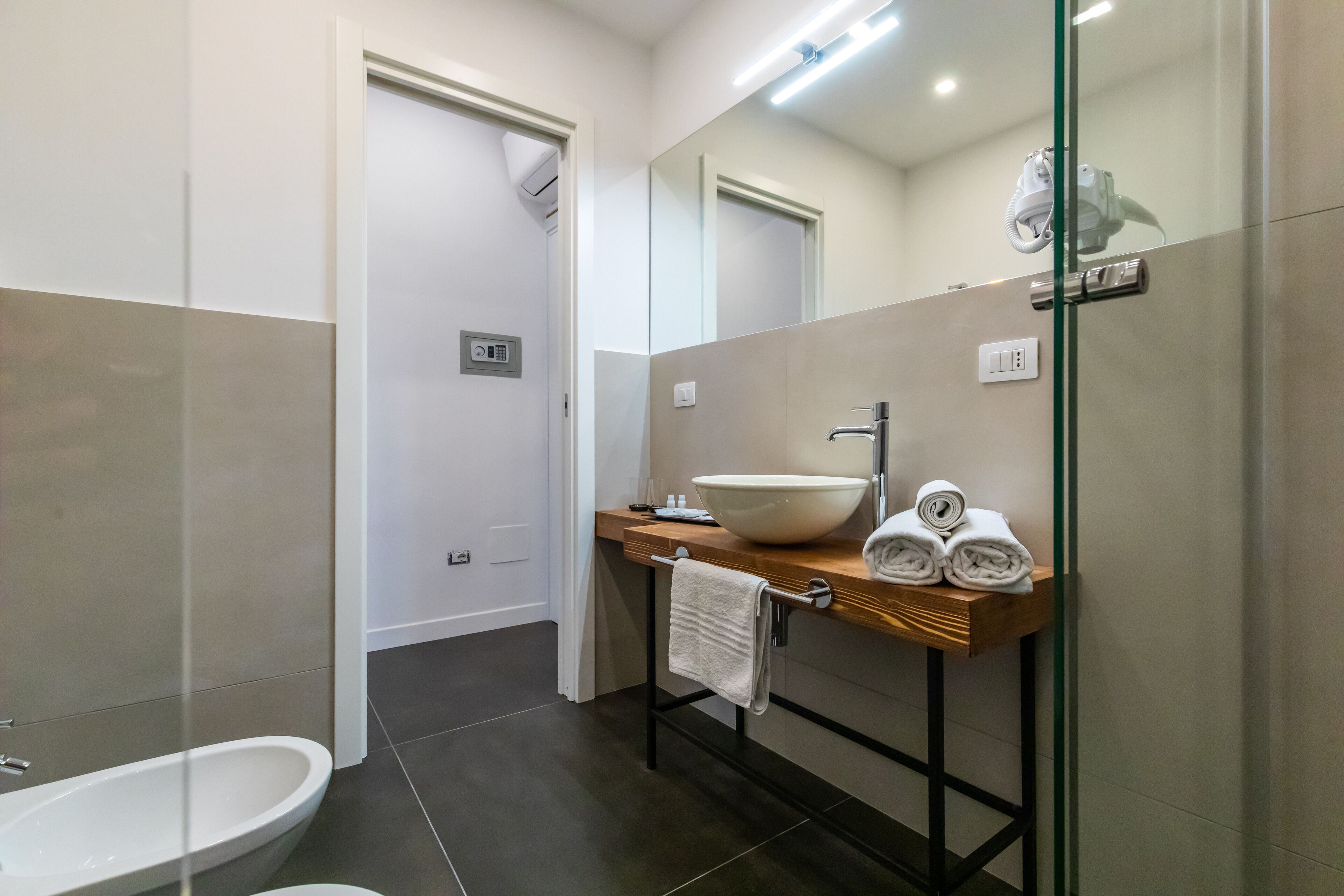 A modern bathroom with a white sink, a large mirror, and a glass shower enclosure.
