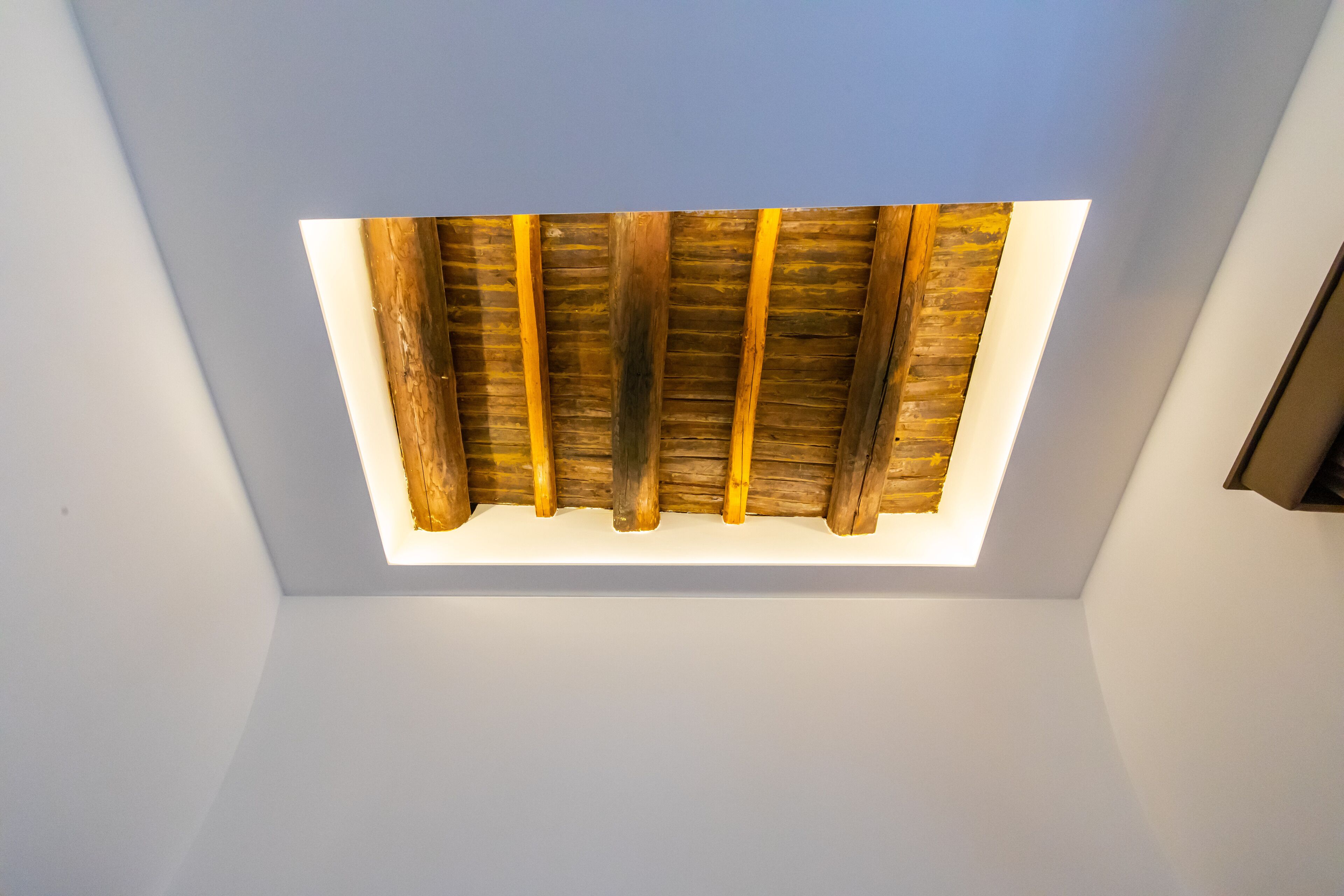 Un plafond avec des poutres apparentes et un luminaire central.