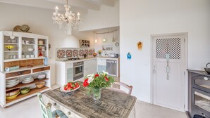 Une cuisine avec une table en bois, des placards blancs et un lustre.