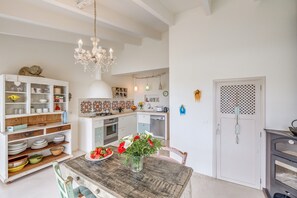 Una cocina con una mesa de madera, armarios blancos y una lámpara de araña.