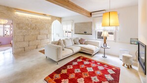 Un salon moderne avec un canapé blanc, un tapis à motifs rouges, un plafond en bois et un lampadaire.