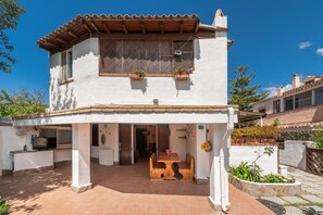 A two-story house with a patio, a TV, and a table with chairs. - Holiday Home "Casa Marisol" on the Beach with Garden, Terrace & Wi-Fi (Quartu Sant' Elena)