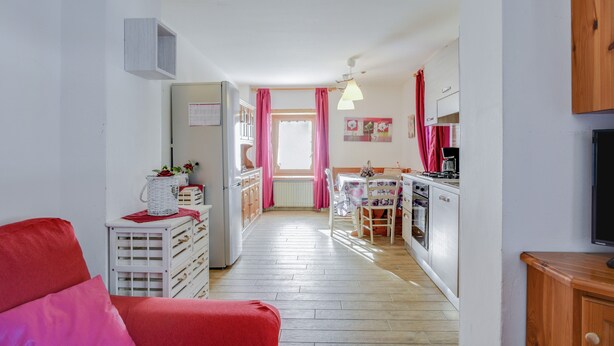 A compact kitchen with a dining area, a refrigerator, and a television. - Spacious Apartment “Cesa Crepaz” with Mountain View, Wi-Fi & Garden (Canazei)