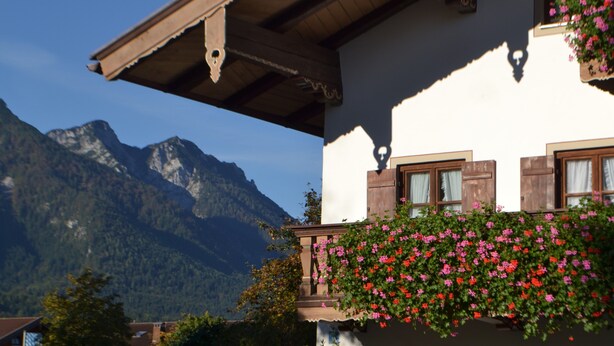Une maison de montagne dotée d’un balcon, de poutres en bois et offrant une vue sur les montagnes.