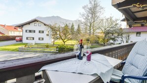 Un balcon avec une table dressée pour deux personnes, une bouteille de vin et deux verres.