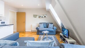 A modern living room with a sofa, a coffee table, and a television. - Luxurious Modern One Bedroom Apartment (Redhill)