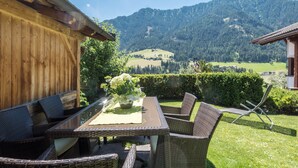 A patio with wicker furniture, a table with a vase, and a view of a mountain. - Holiday Apartment "Christa B1" with Wi-Fi near Various Ski Resorts (Ortisei)