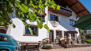 A traditional building with a stone bench, a car, and flower arrangements. - Holiday Apartment "Christa B1" with Wi-Fi near Various Ski Resorts (Ortisei)