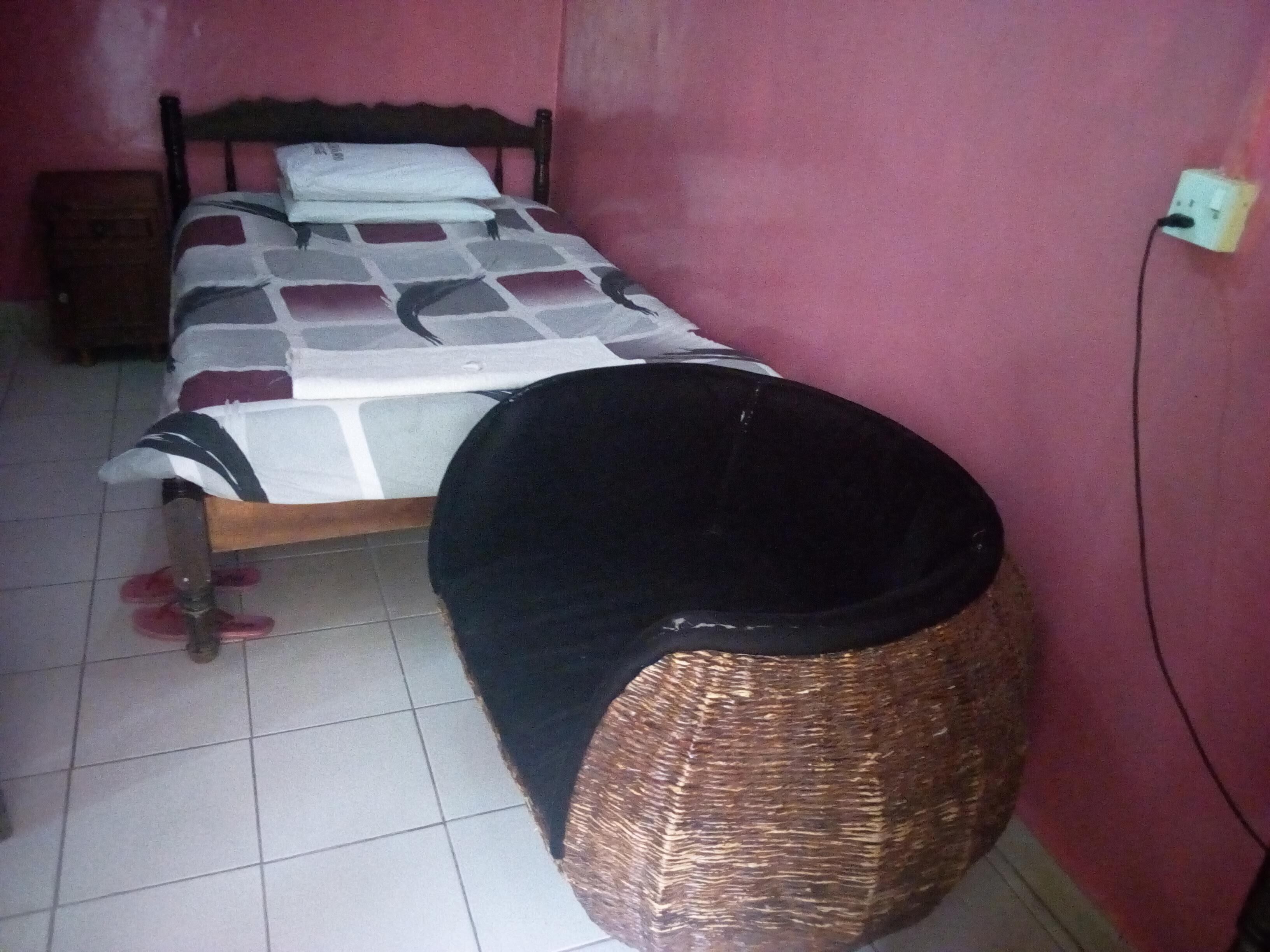 Une chambre à coucher avec un lit, une table de chevet, une prise électrique et un sol carrelé.