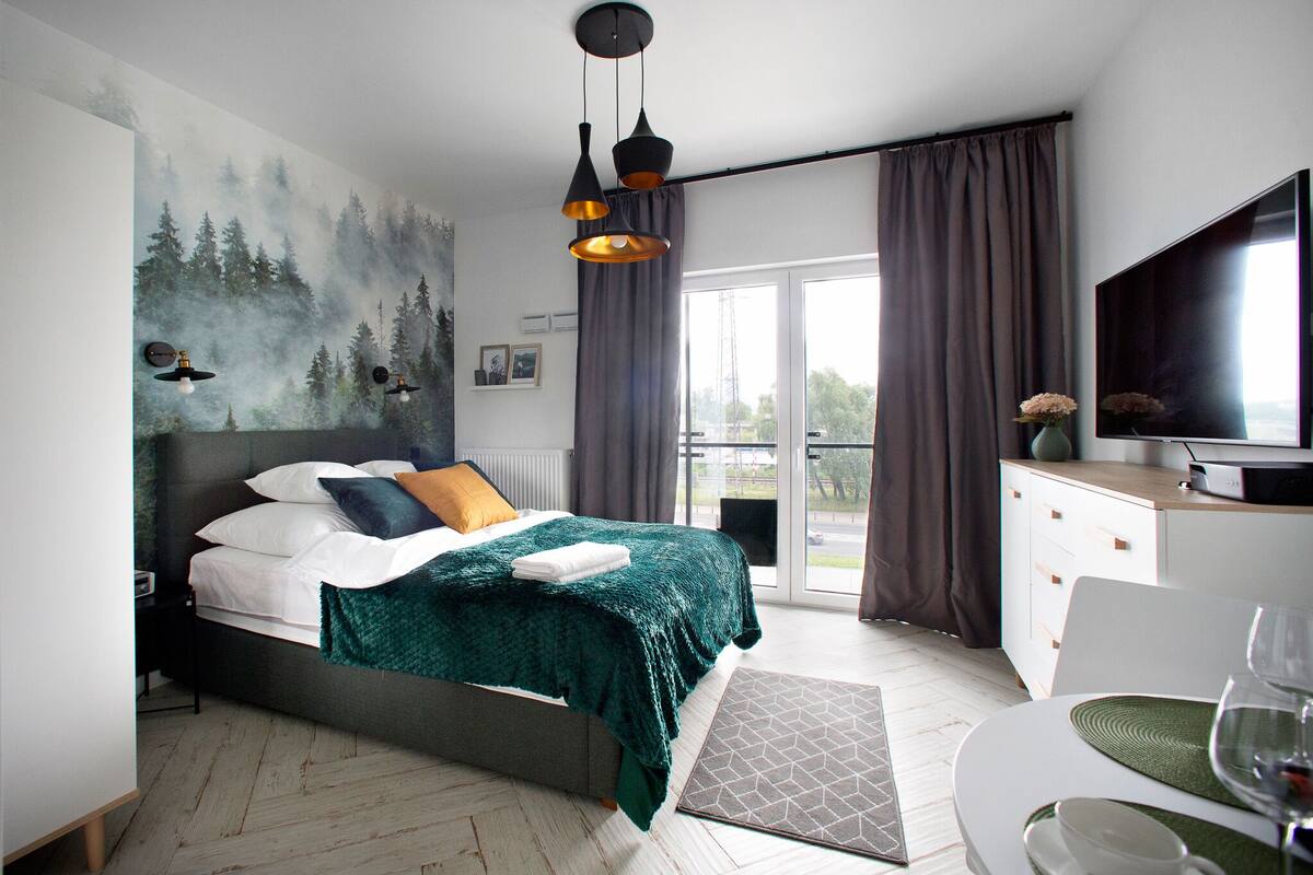 A modern bedroom with a bed, a TV, and a dining area with a table and chairs.