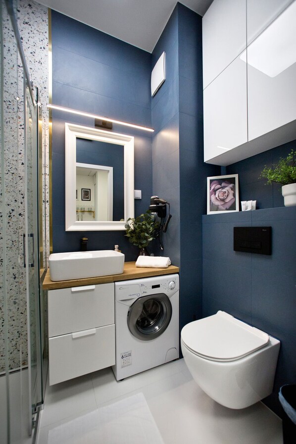 A compact bathroom with a washing machine, a toilet, and a sink.