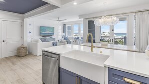 A modern kitchen with a large island, a dishwasher, and a view of the ocean. - Stylish Beachfront Condo (Watersound)