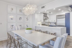 Una cocina moderna con armarios blancos, un refrigerador de acero inoxidable y una isla central con asientos.