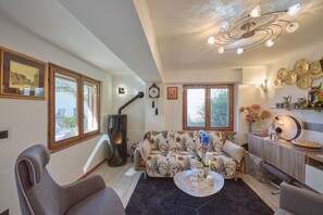Un salon comprenant un canapé, des fauteuils, une table basse, une cheminée et un coin repas avec une radio et des fleurs.