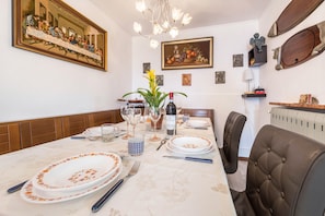 Un coin repas avec une table dressée pour quatre personnes, un lustre, des œuvres d’art encadrées et des objets décoratifs accrochés aux murs.