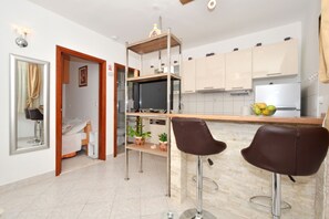 A modern kitchen with a bar area, a dining table, and a small seating area.