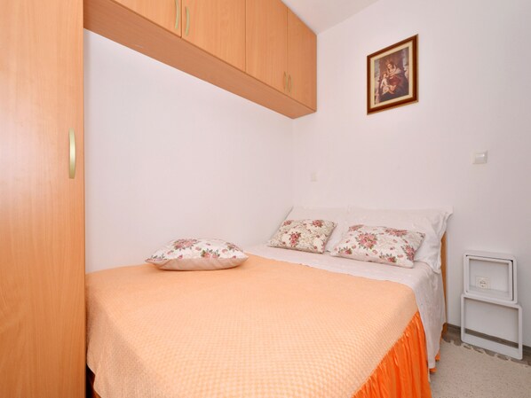 A bedroom with a bed, a nightstand, and a wooden wardrobe. - Tihi Val 3 (Podstrana)