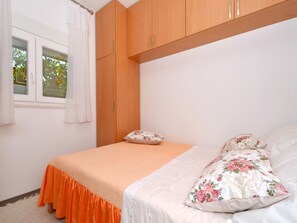 Une chambre à coucher avec un lit, une fenêtre avec des rideaux et une armoire en bois.