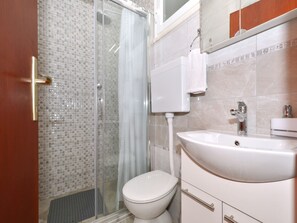 Une salle de bain avec une douche à parois de verre, des toilettes et un lavabo avec un miroir au-dessus.