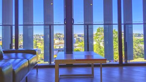 Una habitación con amplios ventanales, una mesa de madera y un sofá de cuero.