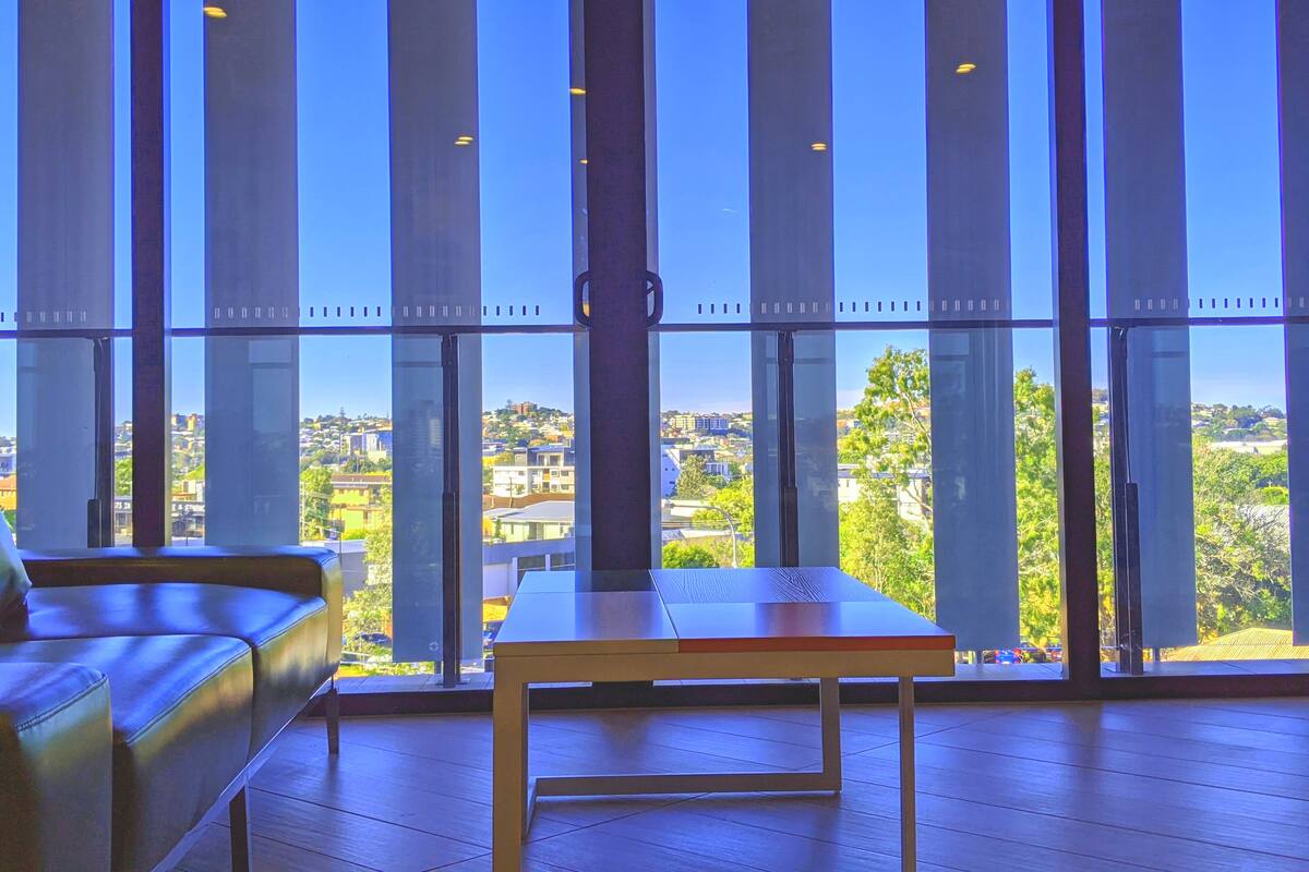 Una habitación con amplios ventanales, una mesa de madera y un sofá de cuero.